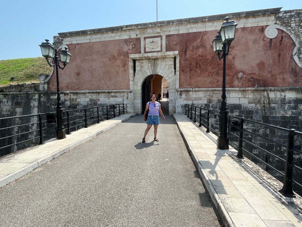 WomN in a purple top and shorts at the entrance to the old fortress. 